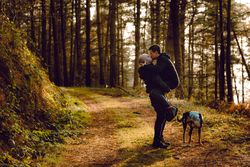Men hugging and kissing on countryside road near dog