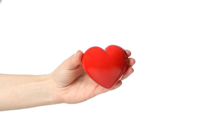 Female hand holds heart, isolated on plain background