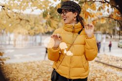 Smiling woman touching leaves on autumn tree