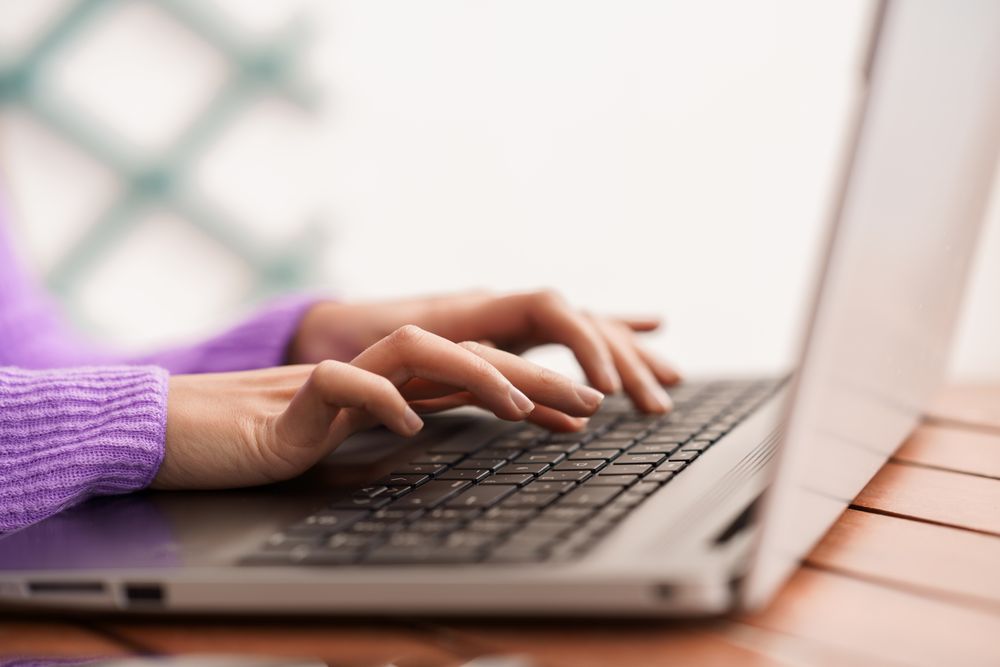 Hands of woman typing on laptop keyboard