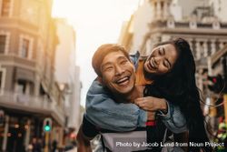 Man giving piggyback ride to his girlfriend outdoors in city street 0PGe7b