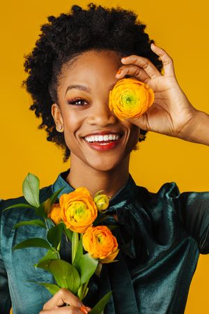 Beautiful Black female model holding ranunculus flowers to her face