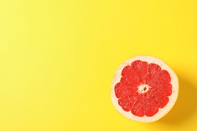 Grapefruit slice on yellow background, space for text