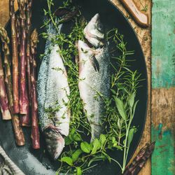 Sea bass with herbs and purple asparagus in dark bowl, square crop