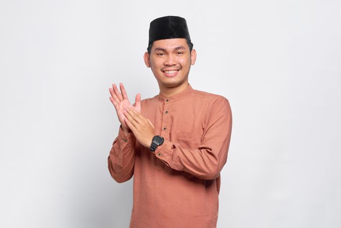 Muslim man in kufi head wear clapping his hands