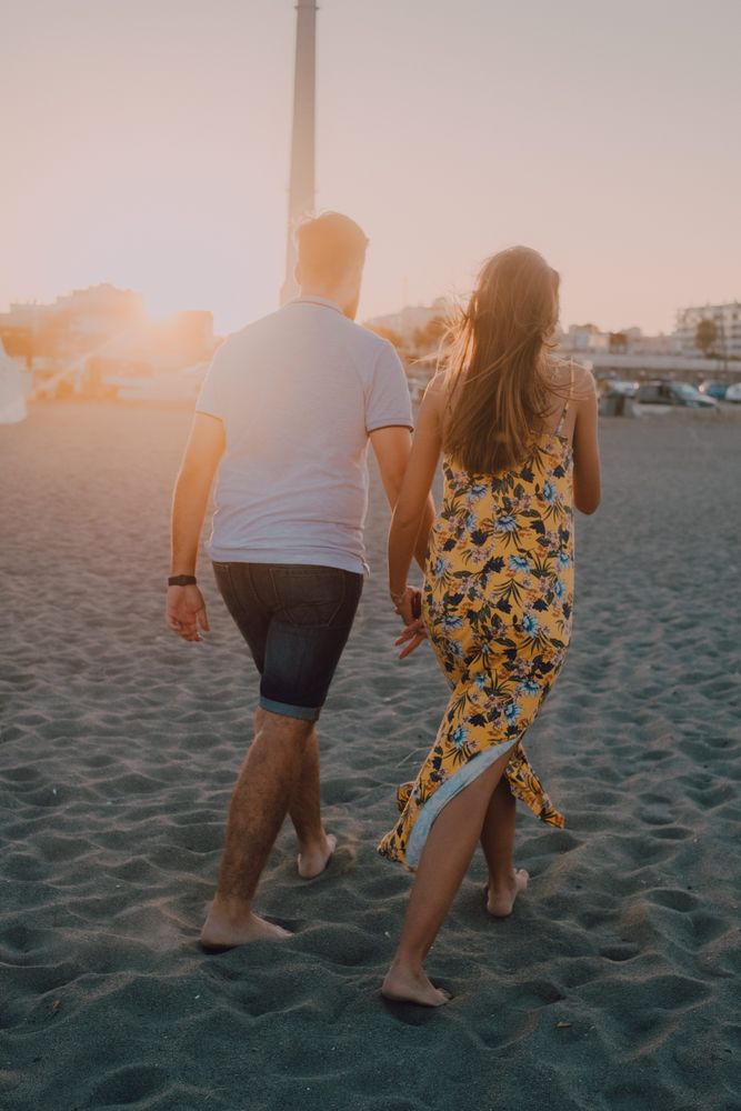 Lovely couple walking holding hands on sandy beach