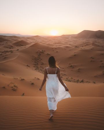 Woman in white dress walking in desert