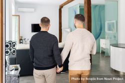Two men holding hands and standing in the living room 0KQ9y4