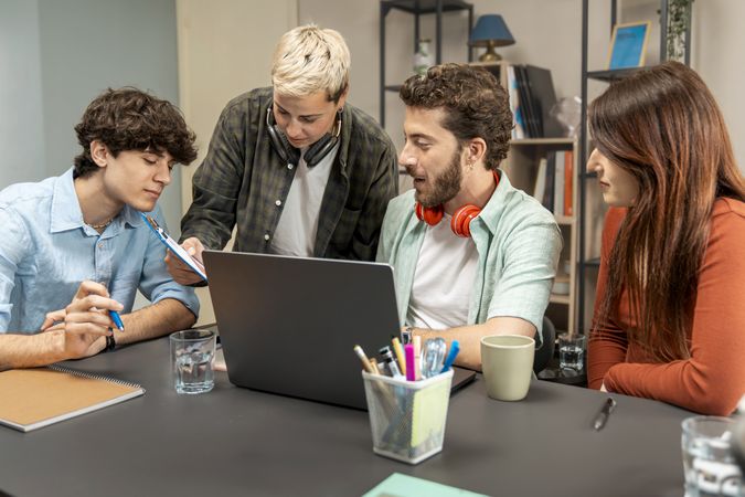 Diverse creative team reviewing project on laptop in casual modern office