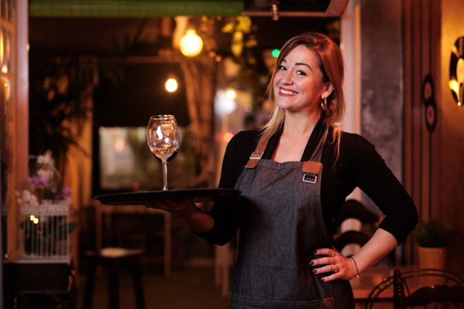 Cheerful waitress holding tray with wineglasses