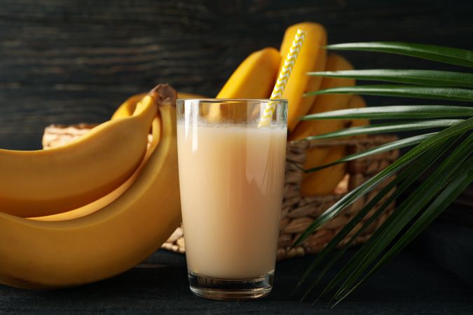 Bananas, juice and palm branch on wooden background. Fresh fruit