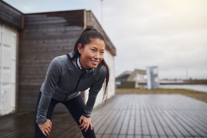 Happy woman leaning down with hands on knees after a run