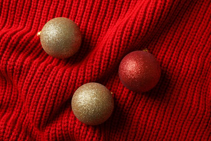 Christmas balls on red sweater background, space for text