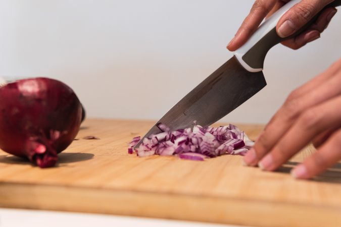 Crop woman cutting onion in kitchen