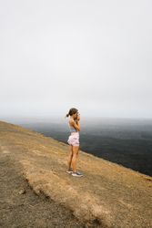 Side view of woman taking picture of sea from hill