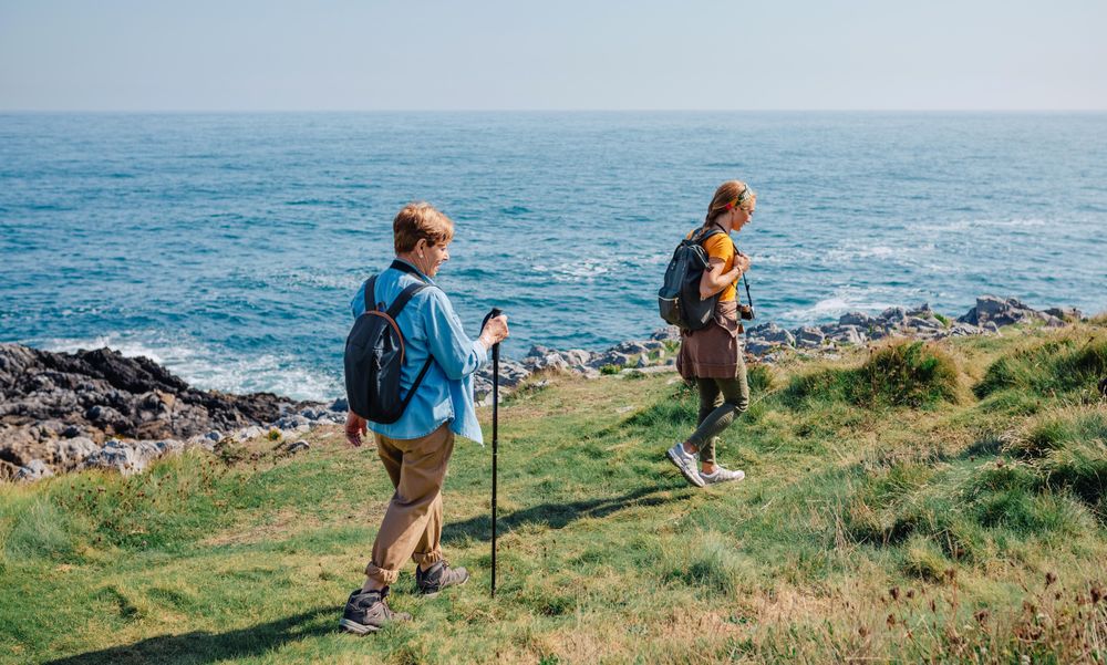 Mother and daughter hiking on beautiful day by the ocean