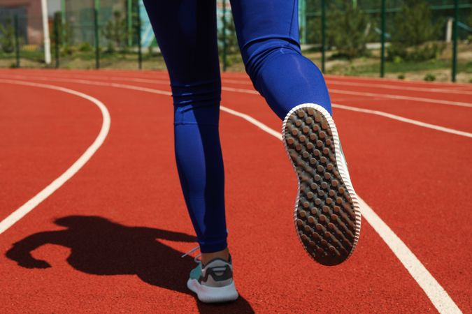Girl running on red athletic track. Sport concept