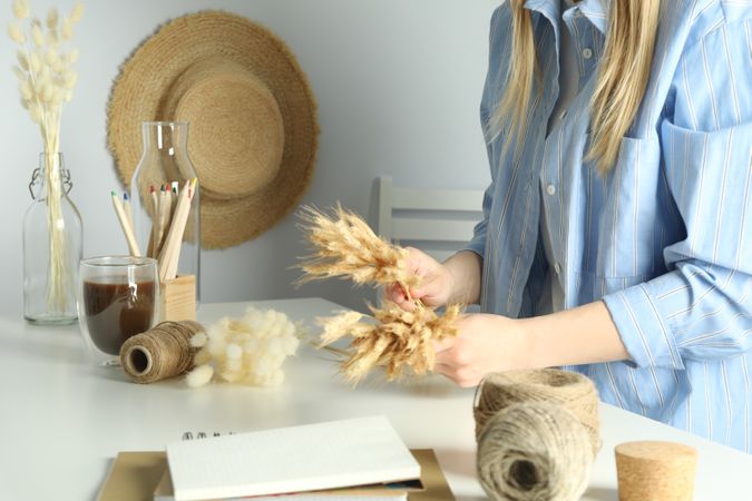 Woman in blue striped shirt arranging dried flowers