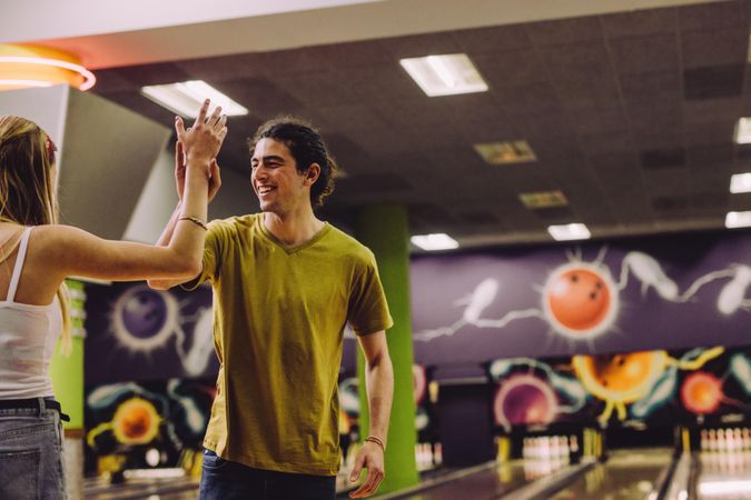 Friends celebrating bowling strike with high five