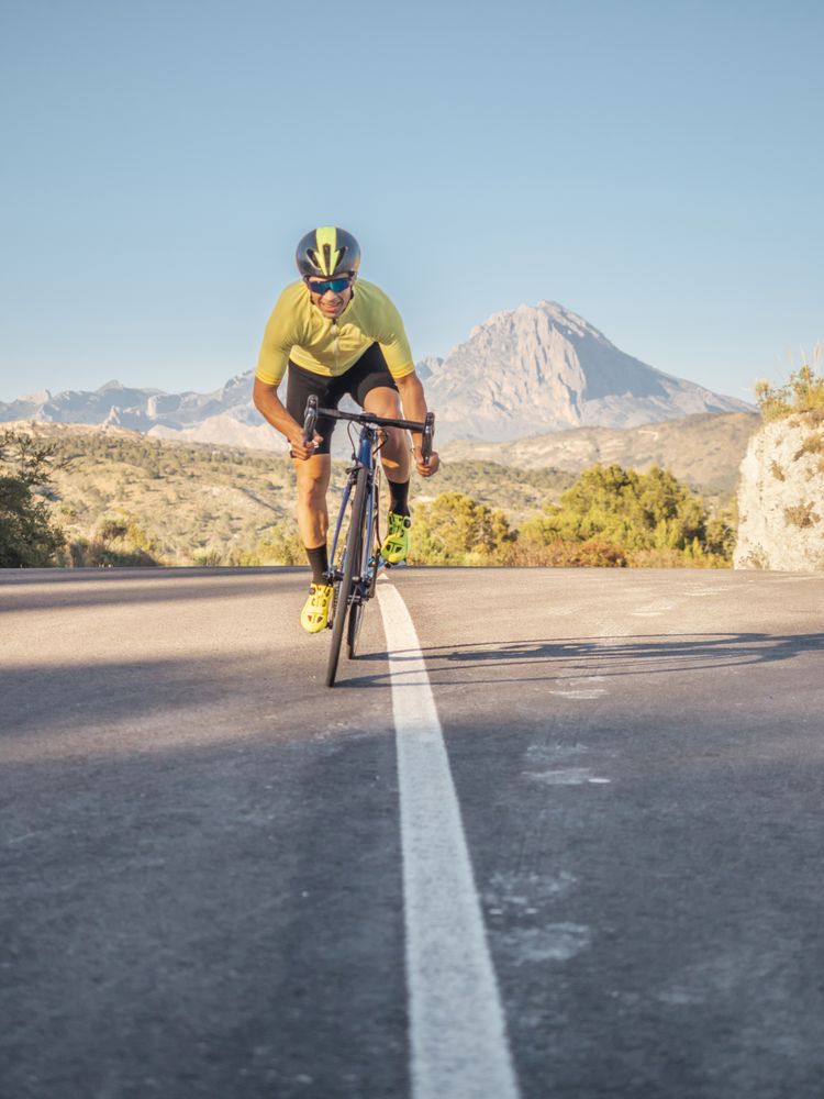 healthy man riding a bicycle on a mountain road in a sunny day