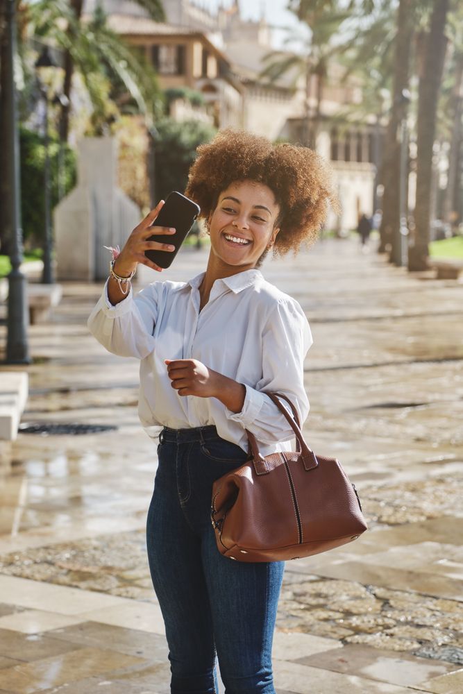Positive Black female taking selfie on street
