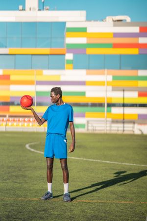 Black teenager with football ball against sky