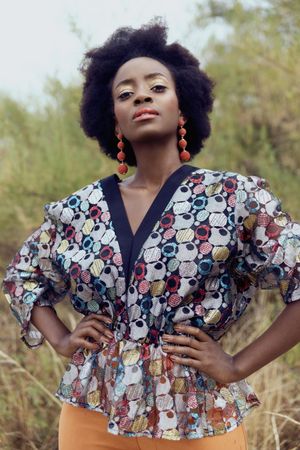 Woman with afro hair wearing patterned shirt standing outdoor