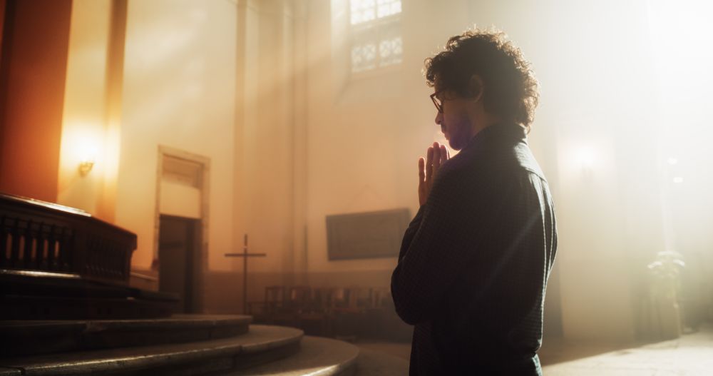 Side View: Christian Man Getting on his Knees and Starting to Pray in a Church.