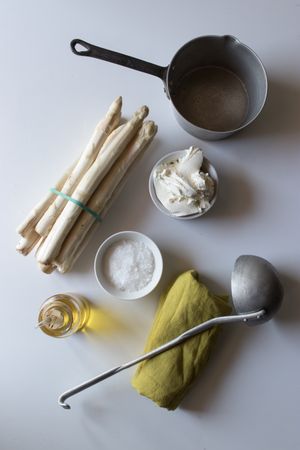 Asparagus and cream amidst kitchenware and condiments