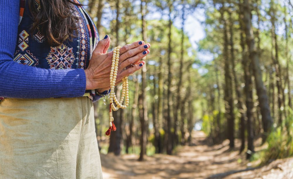 Close up of clasping hands holding a japa mala.  Copy space