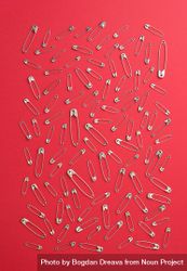 Scattered safety pins on red background 48ZoK0