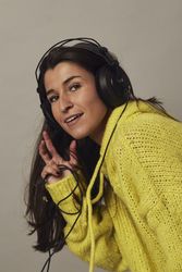 Playful young woman listening to music in studio