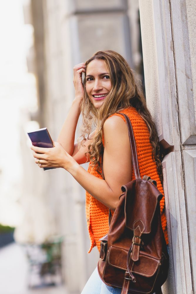 Woman carrying rucksack and holding a mobile in the city