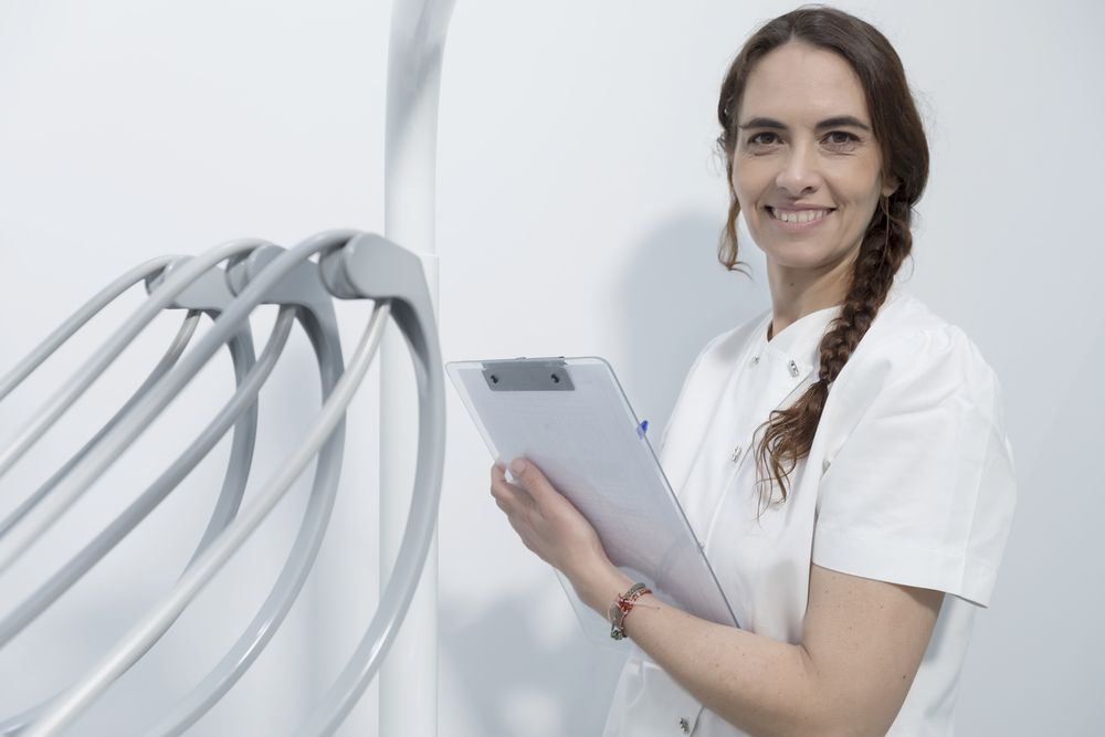 Portrait of a young woman dentist, writing in document, on background dental clinic