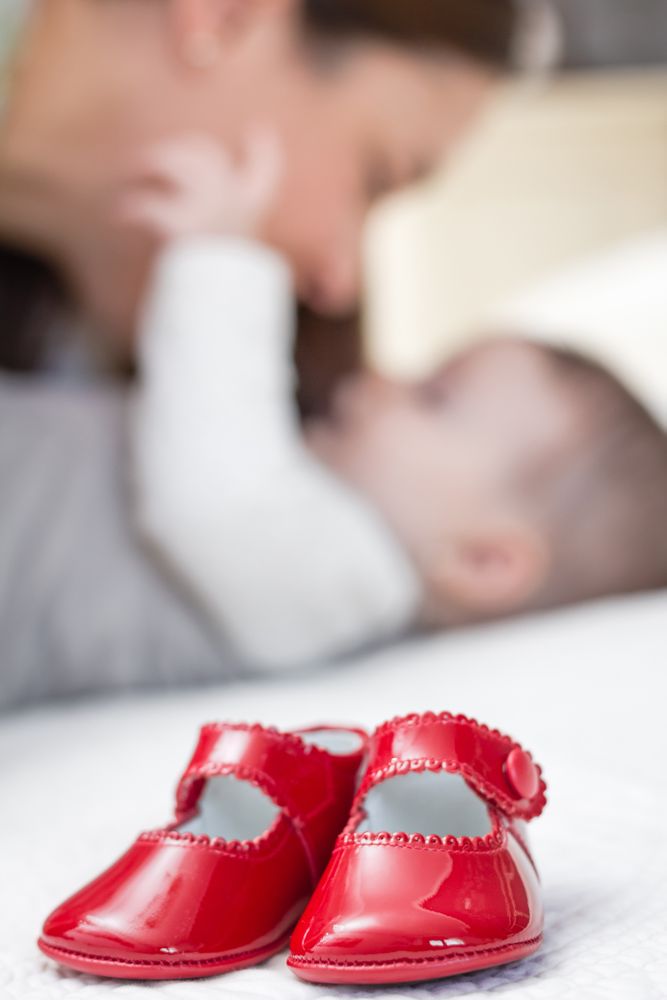 Baby red shoes pair and babe on the background