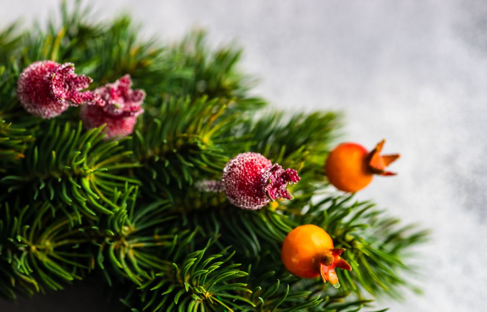 Close up of Christmas wreath with red berry detail on marble counter