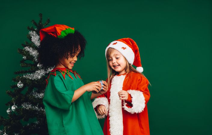 Festive little girls wearing Christmas costumes against green background