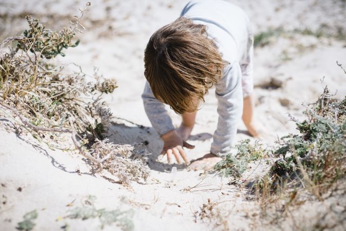 Child crawling in dusty and sandy dune
