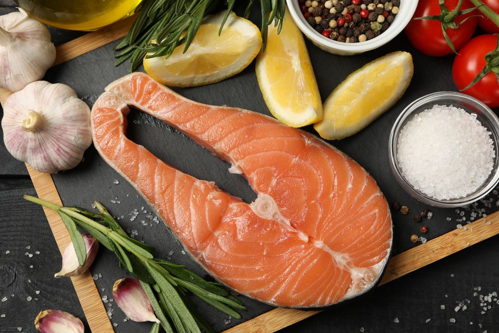 Composition with salmon meat and spices on wooden background, top view