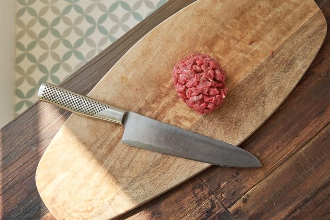 Knife and steak tartar on cutting board on table