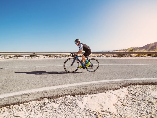 healthy man riding a bicycle on a mountain road in a sunny day
