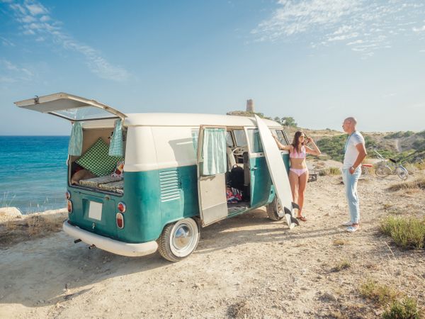 Man and woman chatting leaning on trailer at seaside