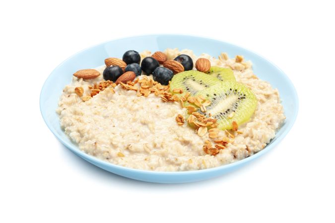 Bowl with oatmeal porridge and ingredients isolated on plain background