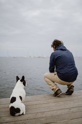 Man and dog sitting on pier