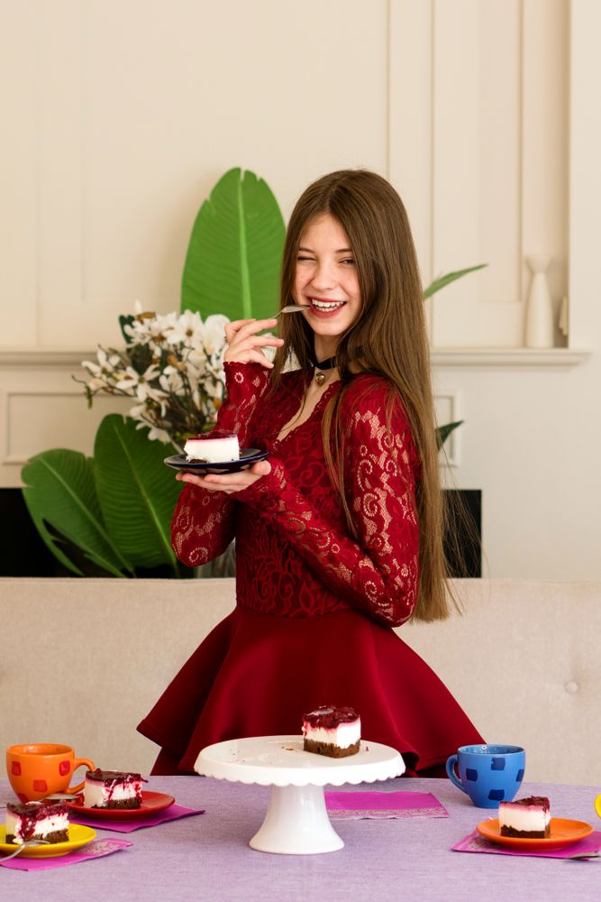 Teen girl winking while holding plate with cheesecake