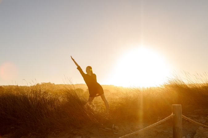Woman posing between field at sunset