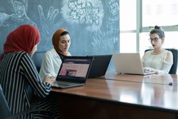 Three women sitting at table and working in office