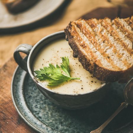 Close up of celery soup in cup with toast, square crop