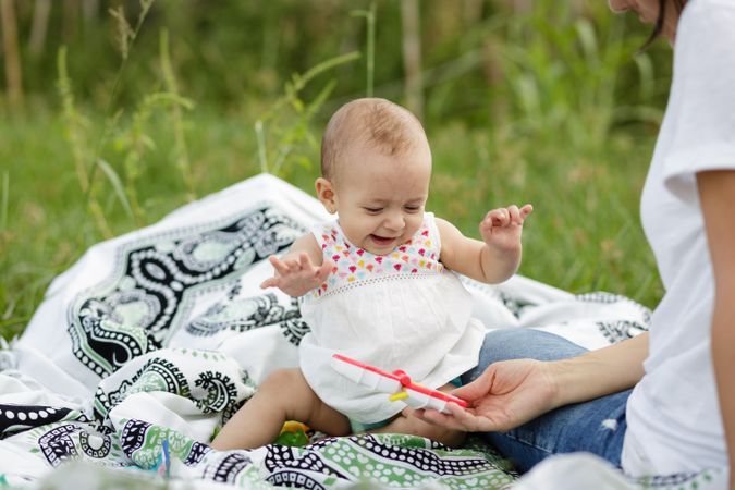 Joyful charming baby sitting on blanket