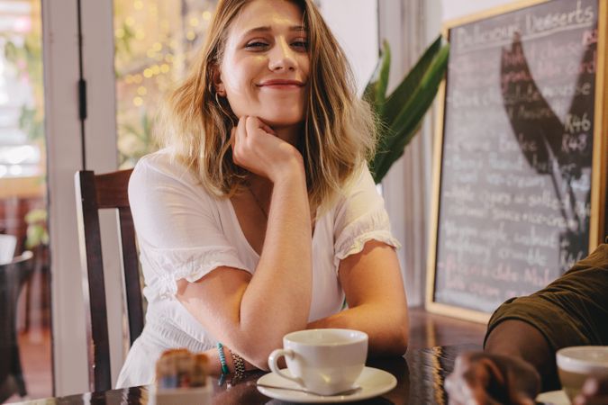 Happy young woman sitting at cafe table with male friend